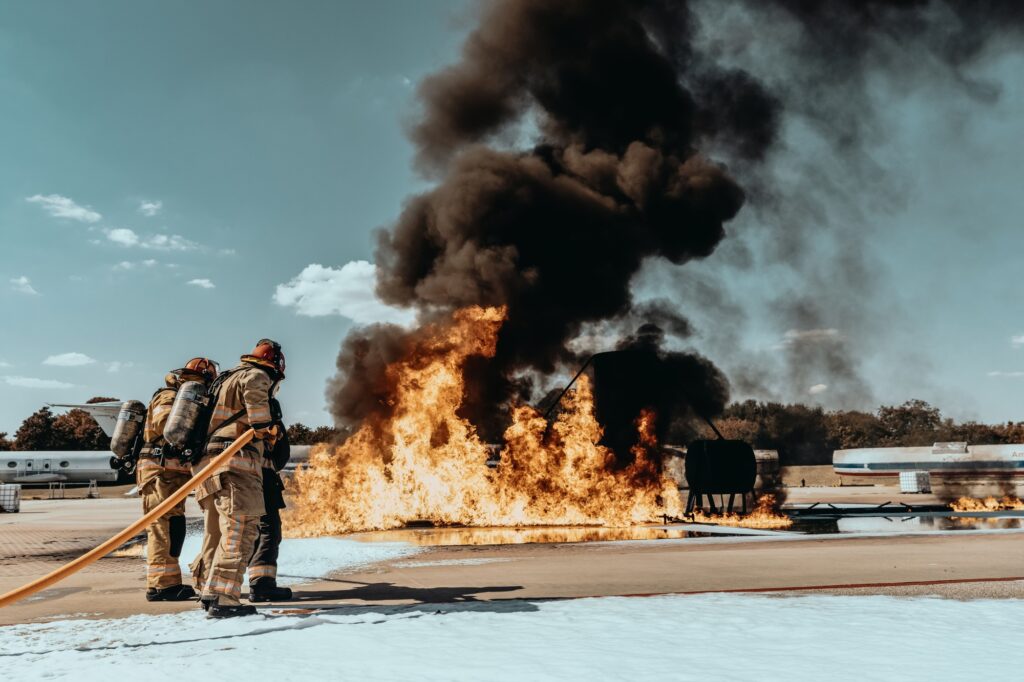 Firefighters extinguishing a large fire at an airport training facility.